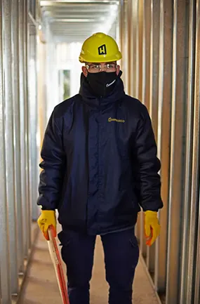 trabajador-de-hiperseco-con-casco-gafas-barbijo-y-guantes-en-casa-de-steel-framing